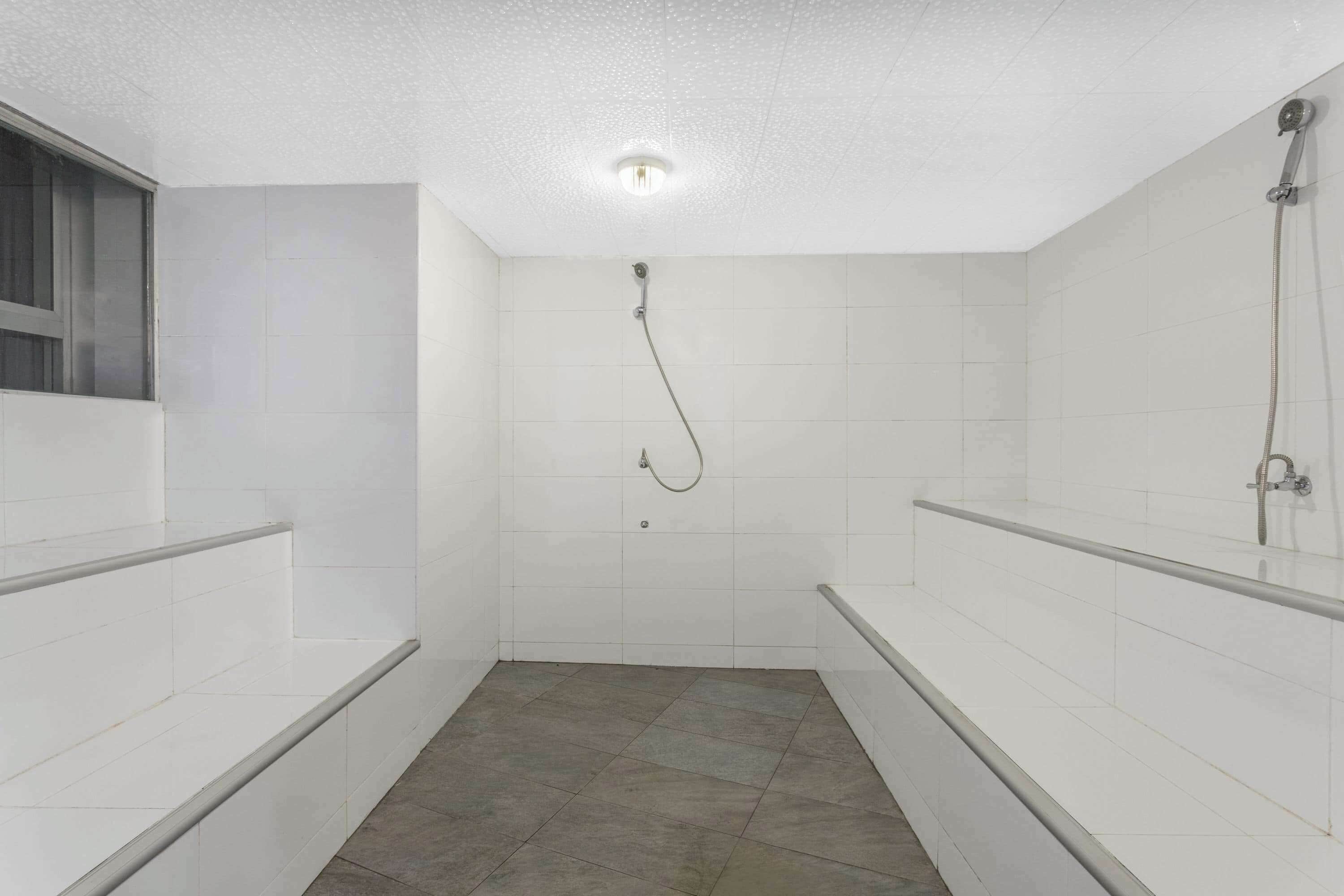 A modern bathroom with white tiles, a shower, and a bathtub.