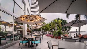 Un espace extérieur aménagé pour les repas, avec des tables, des chaises, des parasols et des plantes en pot.