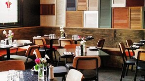 A restaurant interior with multiple tables and chairs, wooden panel walls, and hanging light fixtures. - The Franklin Hotel (Adelaide)