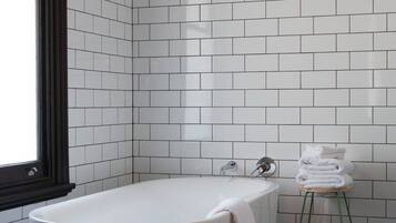 Ein modernes Badezimmer mit einer freistehenden Badewanne, weißen Fliesenwänden und einem Fenster.