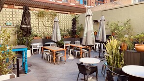 An outdoor patio area with tables and chairs, umbrellas, and potted plants. - The Franklin Hotel (Adelaide)