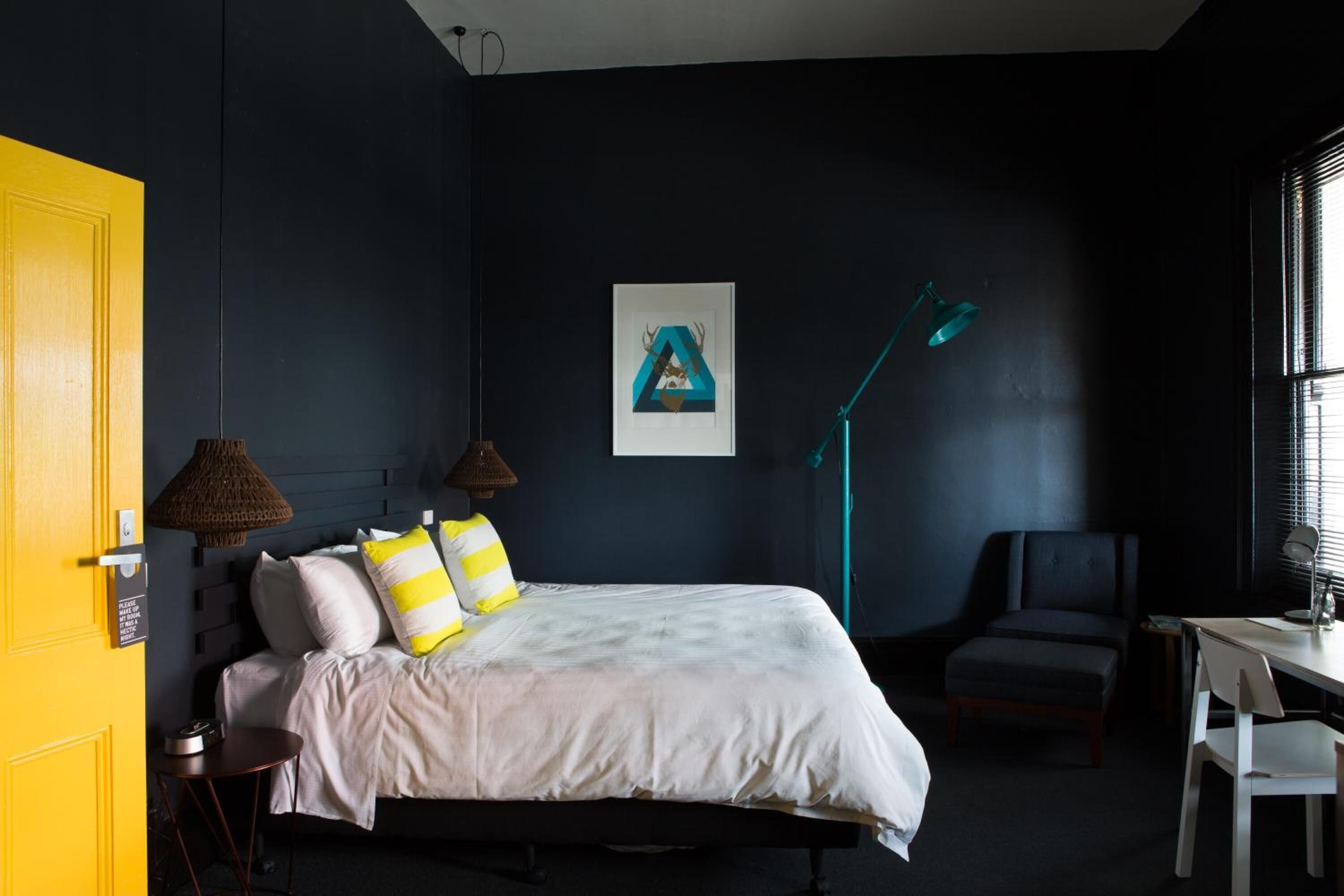 A bedroom with a bed, bedside table, lamp, chair, and a door.