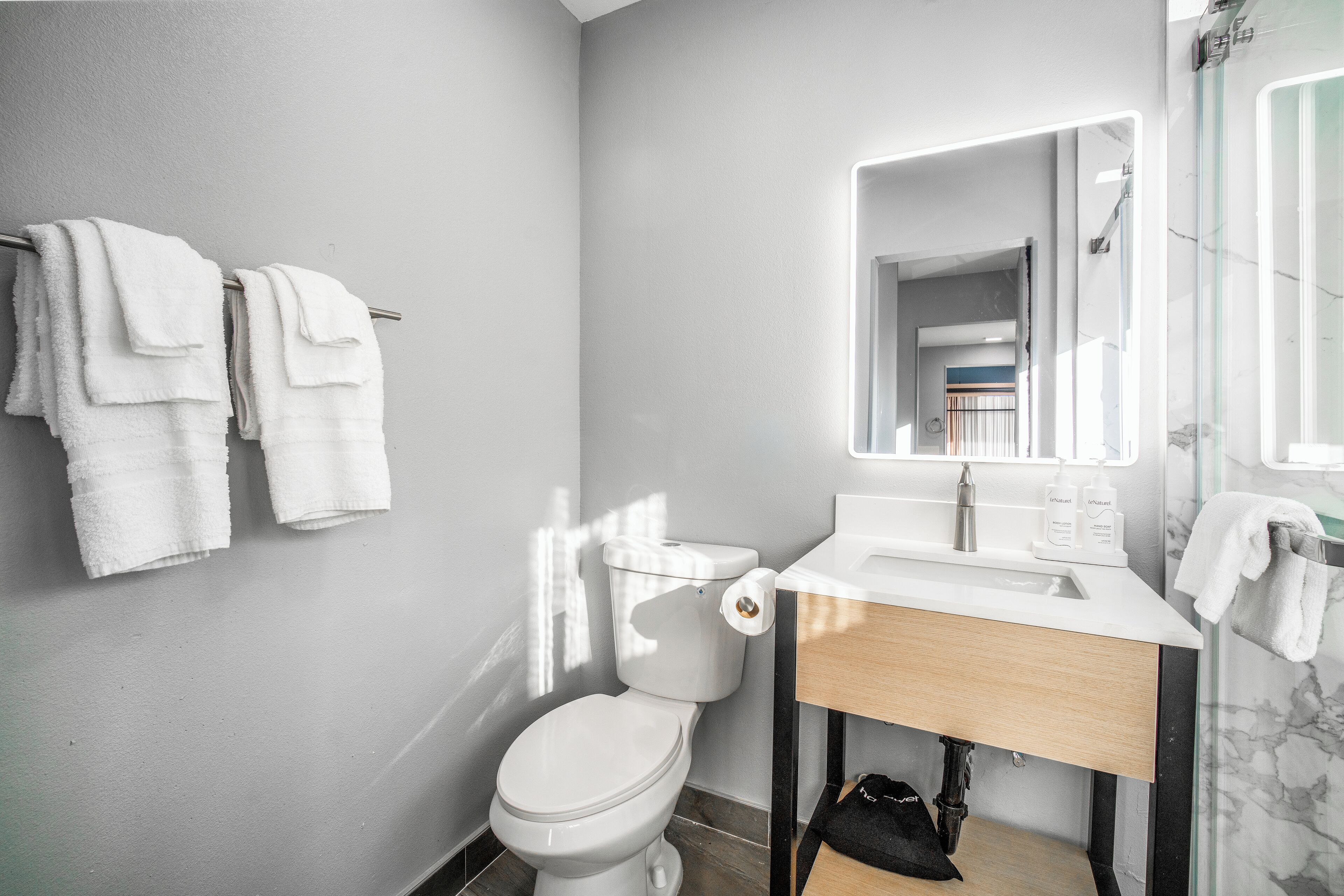 A modern bathroom with a toilet, sink, and mirror.