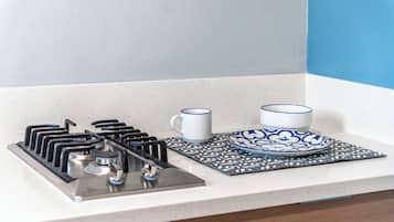 A kitchen with a gas stove, two white mugs, and a blue and white patterned plate on a countertop.