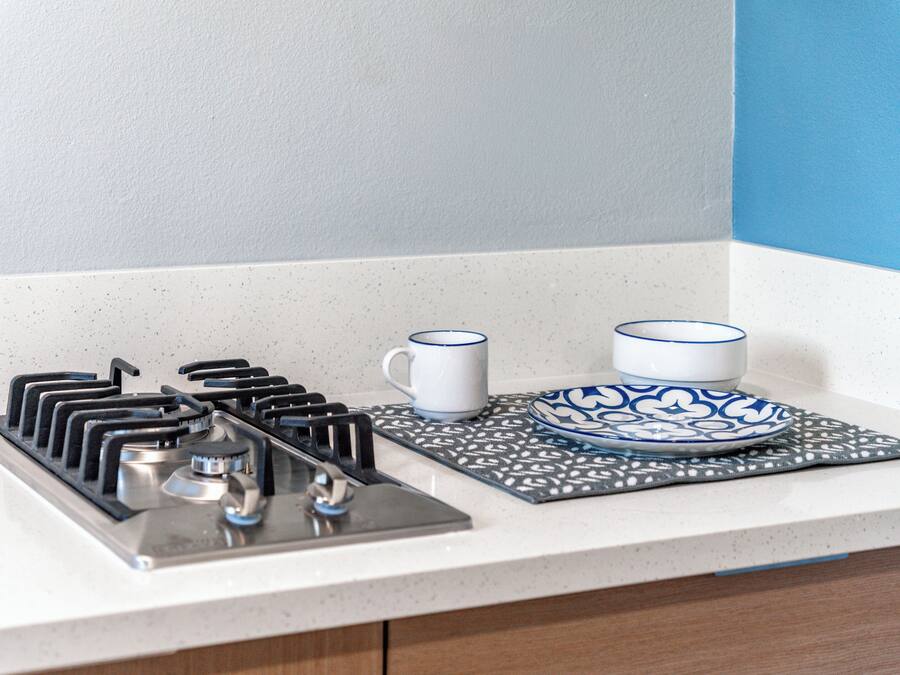 A kitchen with a gas stove, two white mugs, and a blue and white patterned plate on a countertop.