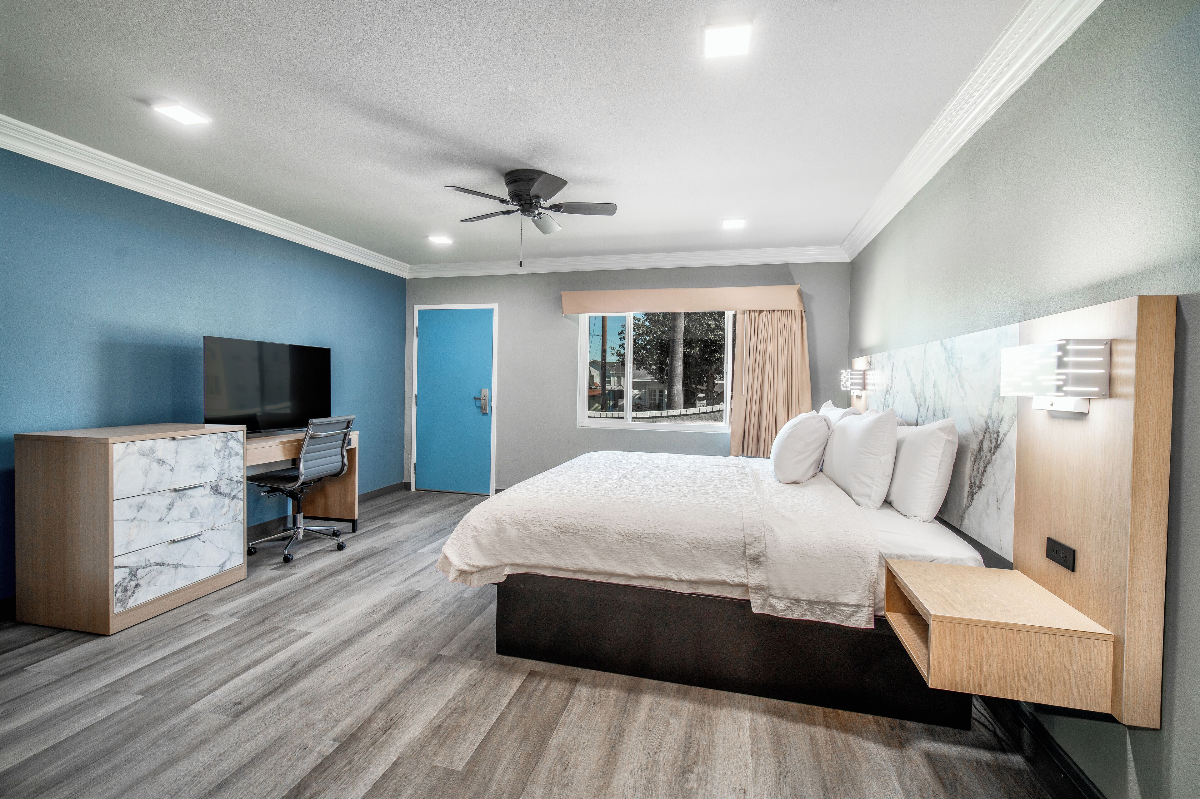 Un dormitorio moderno con cama, escritorio y televisor.
