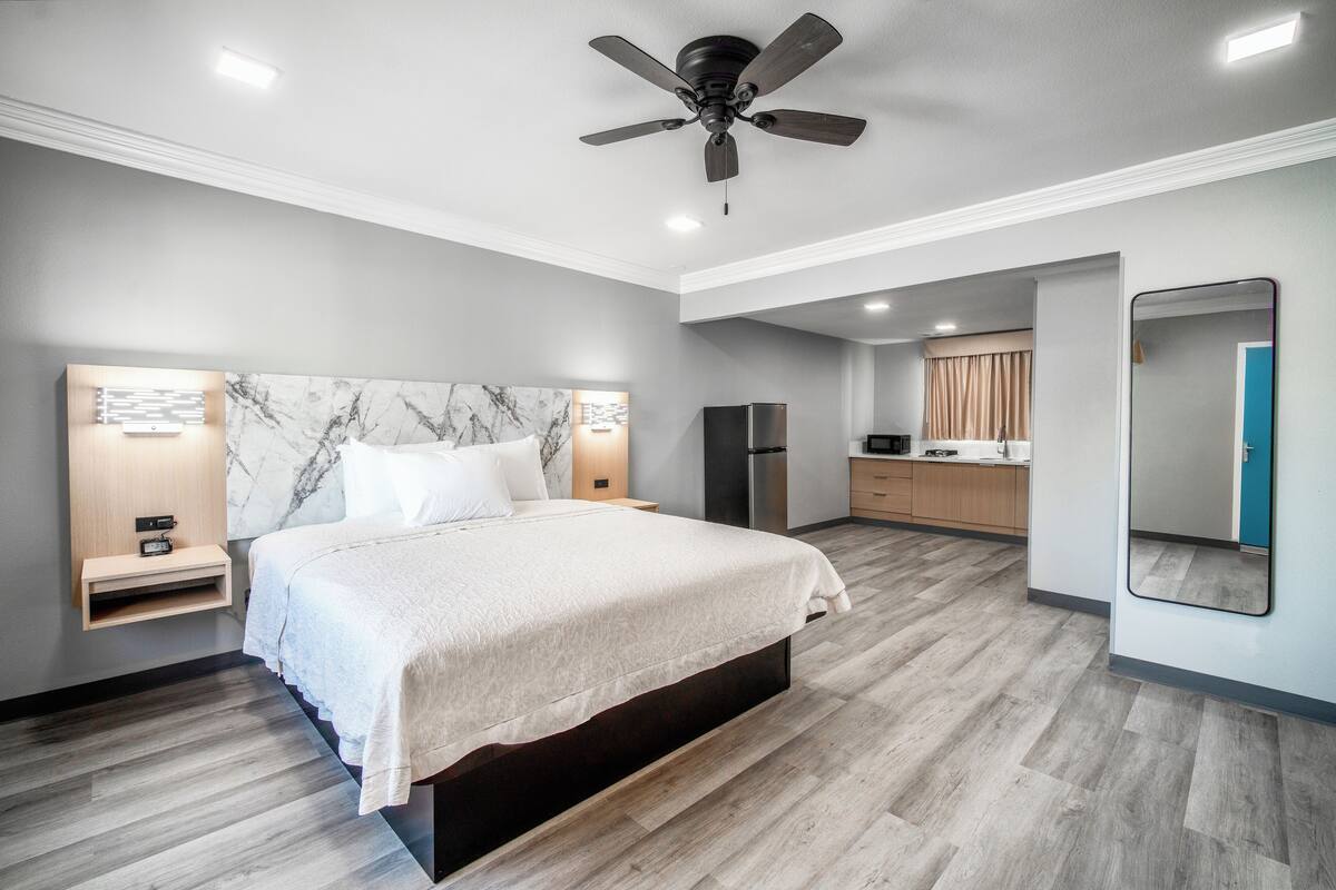Un dormitorio moderno con una cama grande, ventilador de techo y armario empotrado.