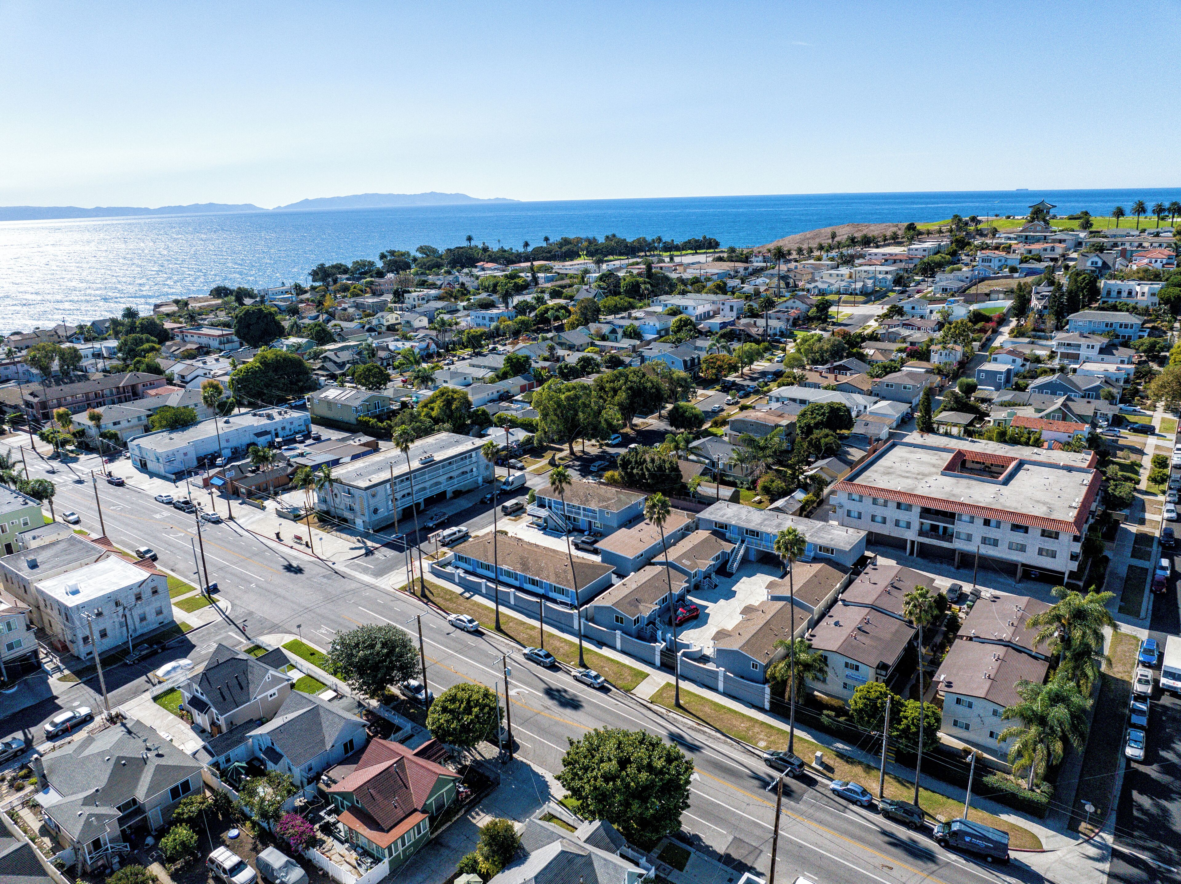 Vista aérea de una zona residencial costera con casas, calles y una vista despejada del océano.