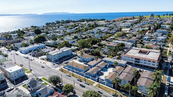 An aerial view of a coastal residential area with houses, streets, and a clear view of the ocean.