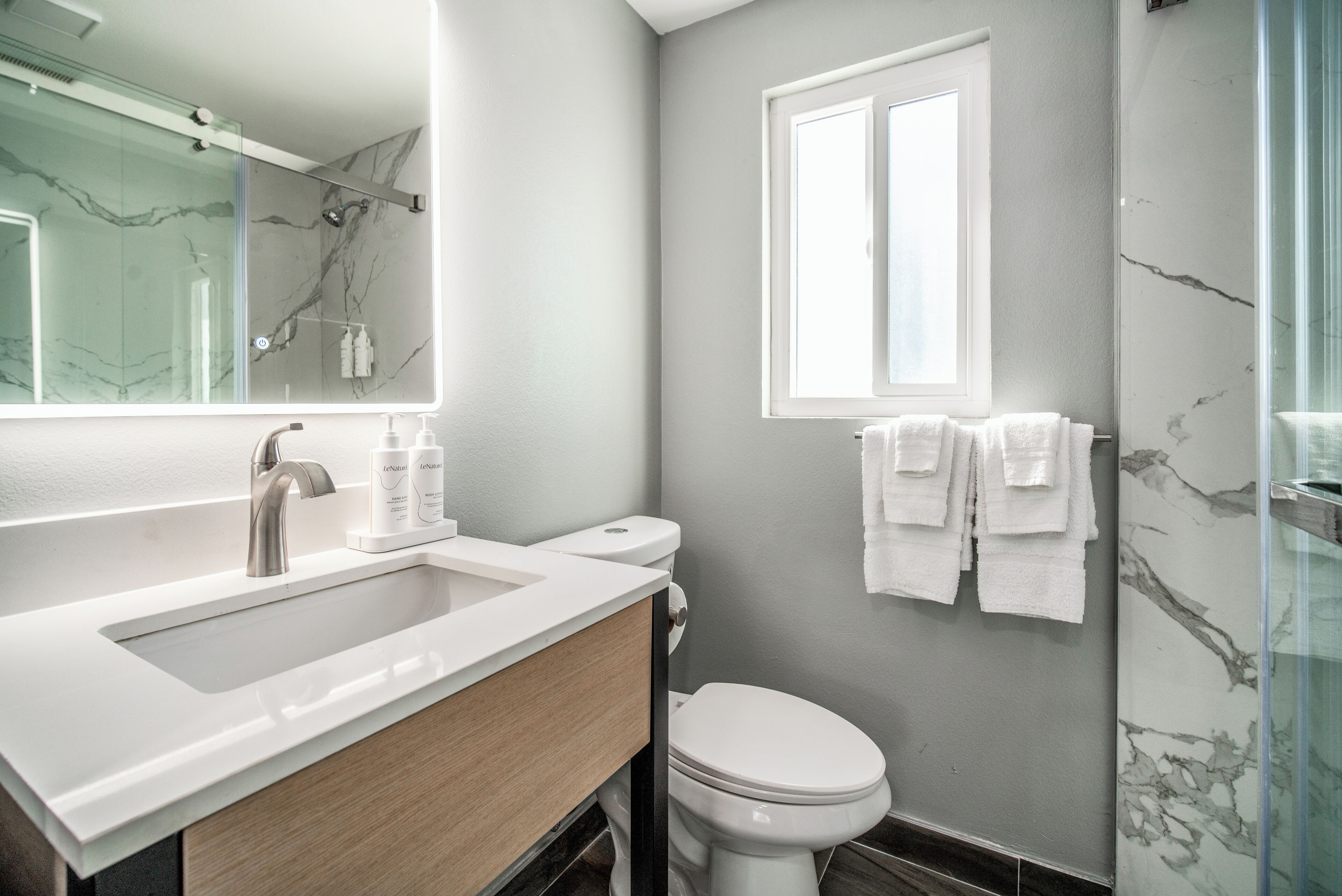 A modern bathroom with a white sink, a toilet, and a glass shower enclosure.