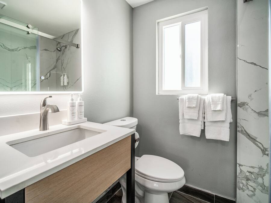 A modern bathroom with a white sink, a toilet, and a glass shower enclosure.