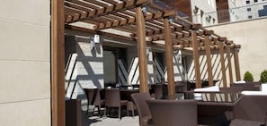 An outdoor seating area with wicker furniture and a wooden pergola structure. - Grand Park Hotel (Ramallah)
