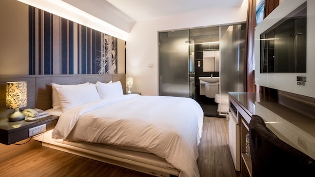 A modern hotel room with a large bed, bedside table with a lamp, and a TV. - Royal Garden Hotel (New Taipei City)