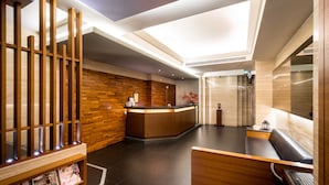 A modern reception area with a wooden reception desk, a seating area, and a reception counter. - Royal Garden Hotel (New Taipei City)