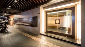 A modern hotel entrance with a tiled floor, a wall-mounted bike rack, and a glass door with a reflection of the interior. - Royal Garden Hotel (New Taipei City)