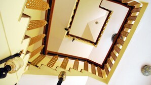 A spiral staircase with a wooden railing and a white wall. - Amritasthanam Guest House And Retreat (Madikeri)