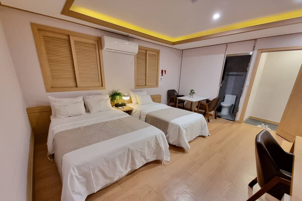A hotel room with two beds, a desk, and a chair.