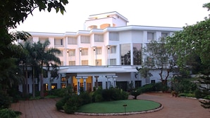 A multi-story hotel with a central courtyard, surrounded by lush greenery and palm trees. - Sangam Hotel in Thanjavur (Thanjavur)