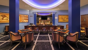 A bar area with a counter, seating, and a television screen. - Sangam Hotel in Thanjavur (Thanjavur)