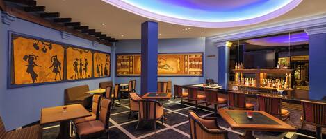 A restaurant with a bar area, multiple seating options including booths and tables, and a staircase leading to an upper level.