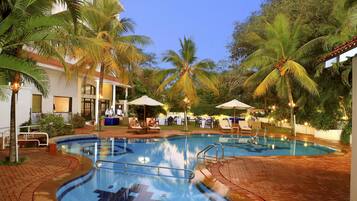 Relax by the pool surrounded by lush greenery and lounge under the shade of umbrellas.