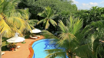 Una piscina al aire libre, sombrillas, sillones reclinables de piscina