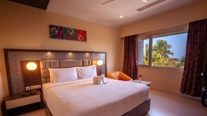 A hotel room with a large bed, a nightstand, a chair, a window with curtains, and a view of palm trees. - Vinayaga by Poppys Rameshwaram (Rameshwaram)