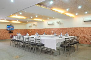 A conference room with a long table, chairs, and a television screen. - East Inn Hotel (New Delhi)