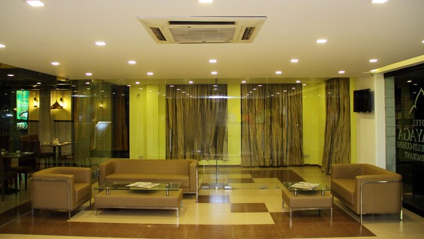 A modern lobby with a glass partition, a central air conditioning unit, and a seating area with sofas and a coffee table. - Vinayaga by Poppys  Kumbakonam (Kumbakonam)