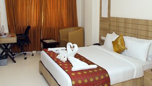 A hotel room with a bed, a desk, a chair, and a curtain. - Vinayaga by Poppys  Kumbakonam (Kumbakonam)