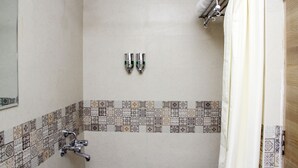 A bathroom with a shower, two faucets, and a tiled floor. - Vinayaga by Poppys  Kumbakonam (Kumbakonam)