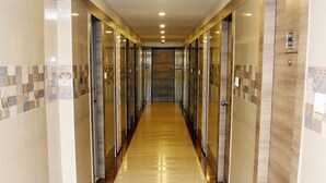A long, narrow hallway with a polished floor, tiled walls, and doors on both sides. - Vinayaga by Poppys  Kumbakonam (Kumbakonam)