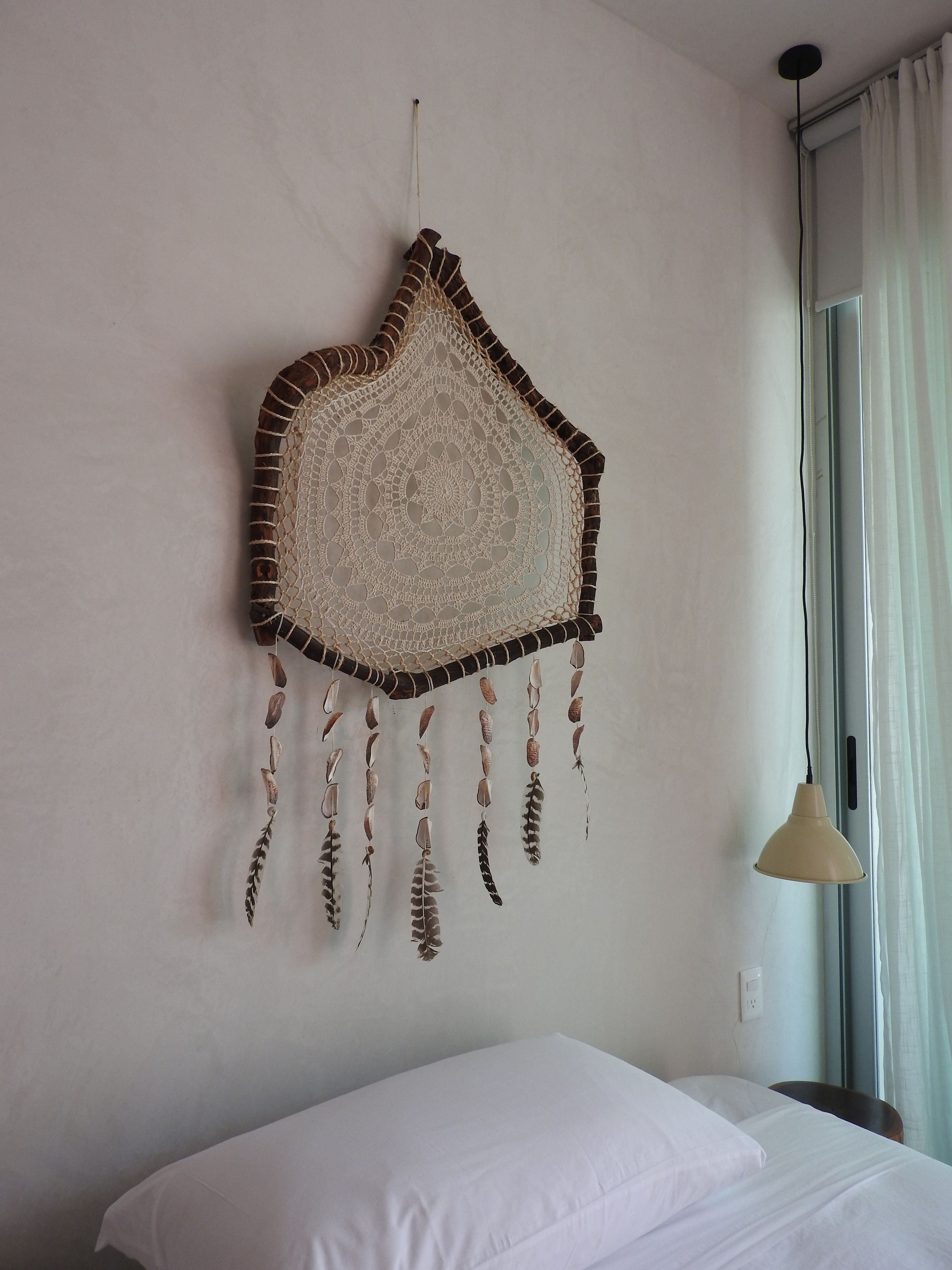 Een kamer met een bed, een wanddecoratie en een raam met gordijnen.