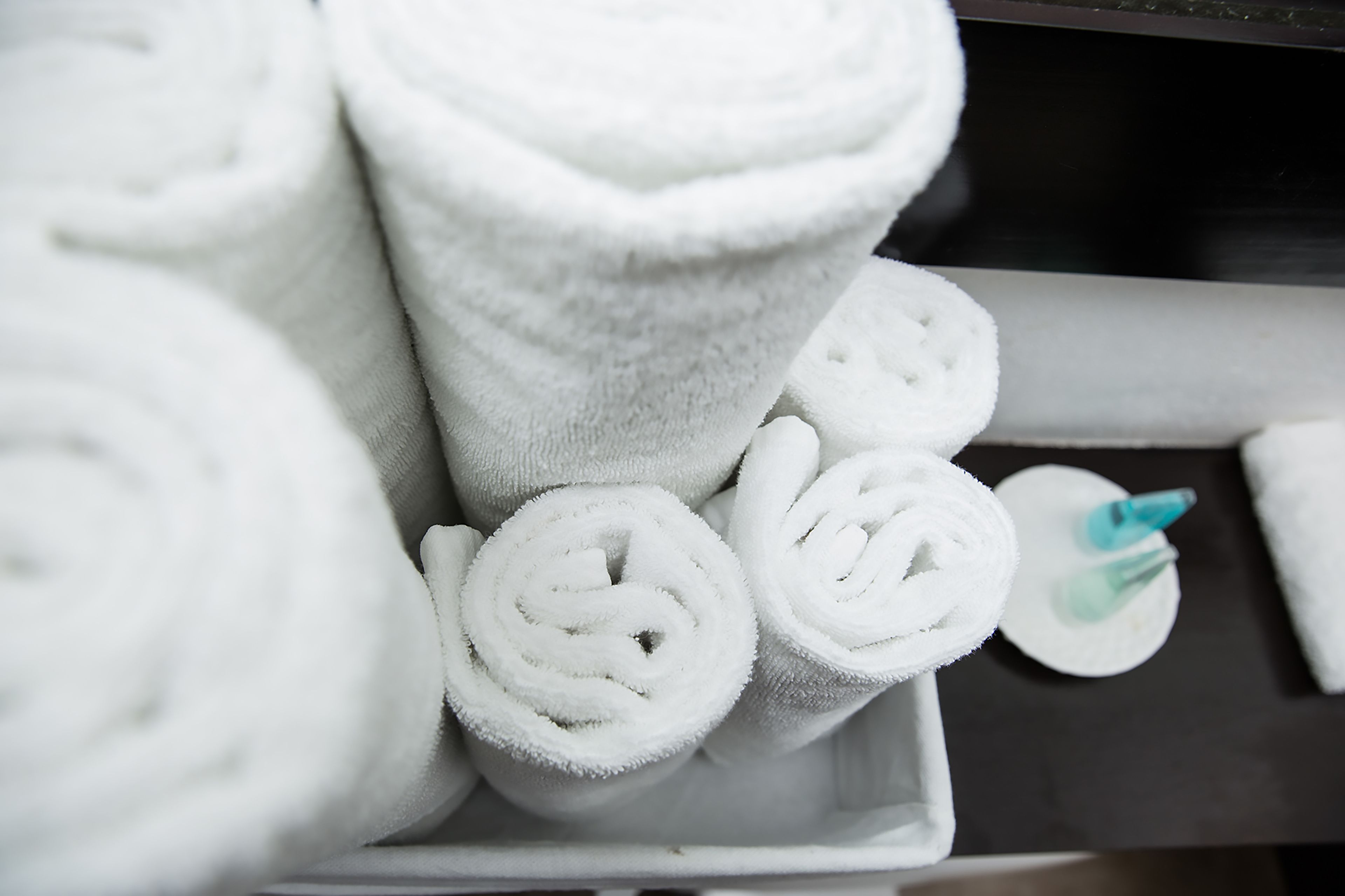A tray with rolled white towels and a small container with a blue object.