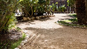 A gravel path bordered by rocks and greenery, leading to a wooden fence. - Villas H2O (Tulum)