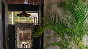 A bathroom with a stone sink, a mirror, and a potted plant. - Villas H2O (Tulum)
