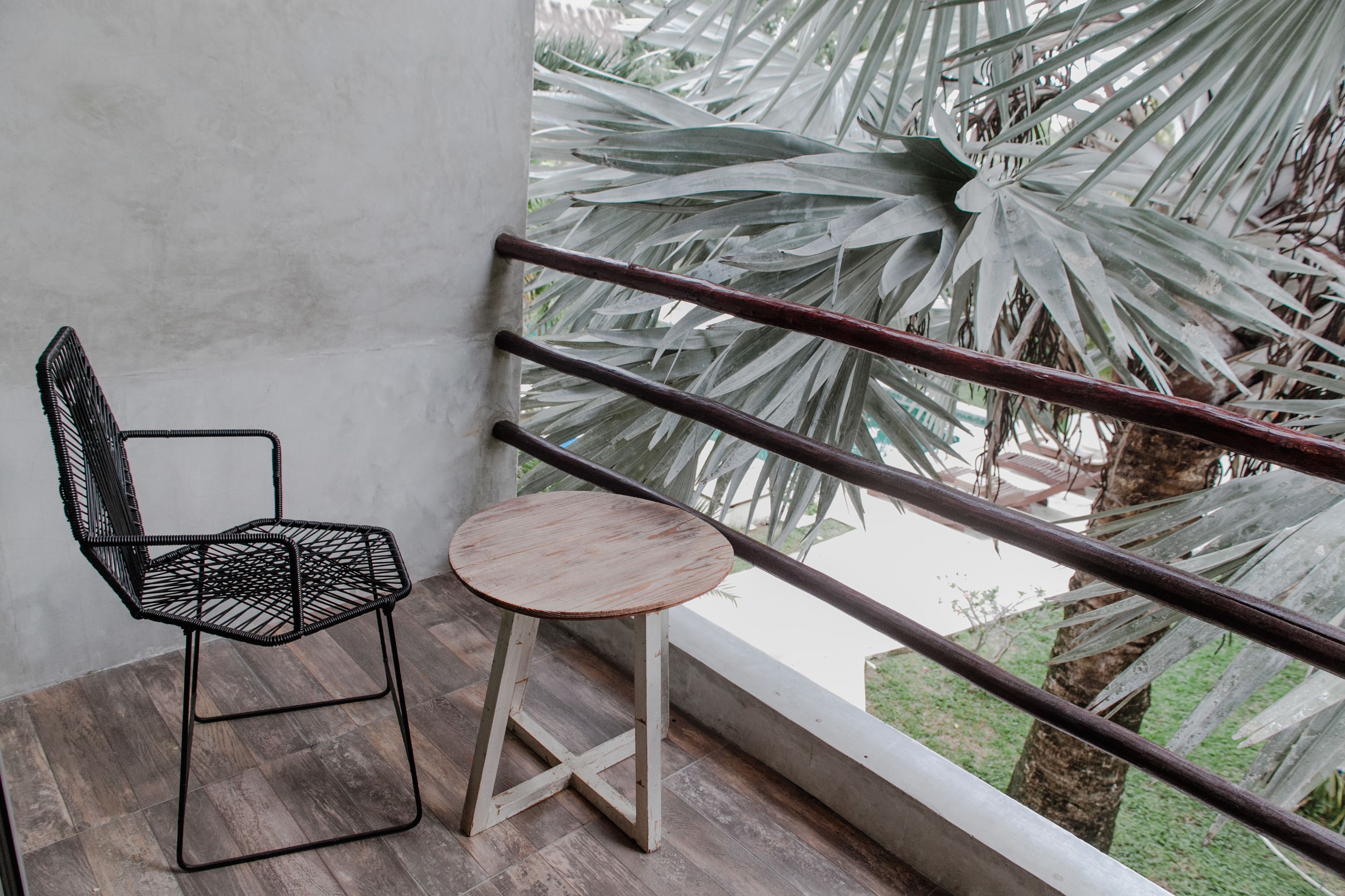 Un balcone con pavimento in legno, una sedia in metallo e un tavolino rotondo.