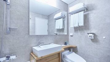 A modern bathroom with a built-in sink, a toilet, a shower, and a mirror.