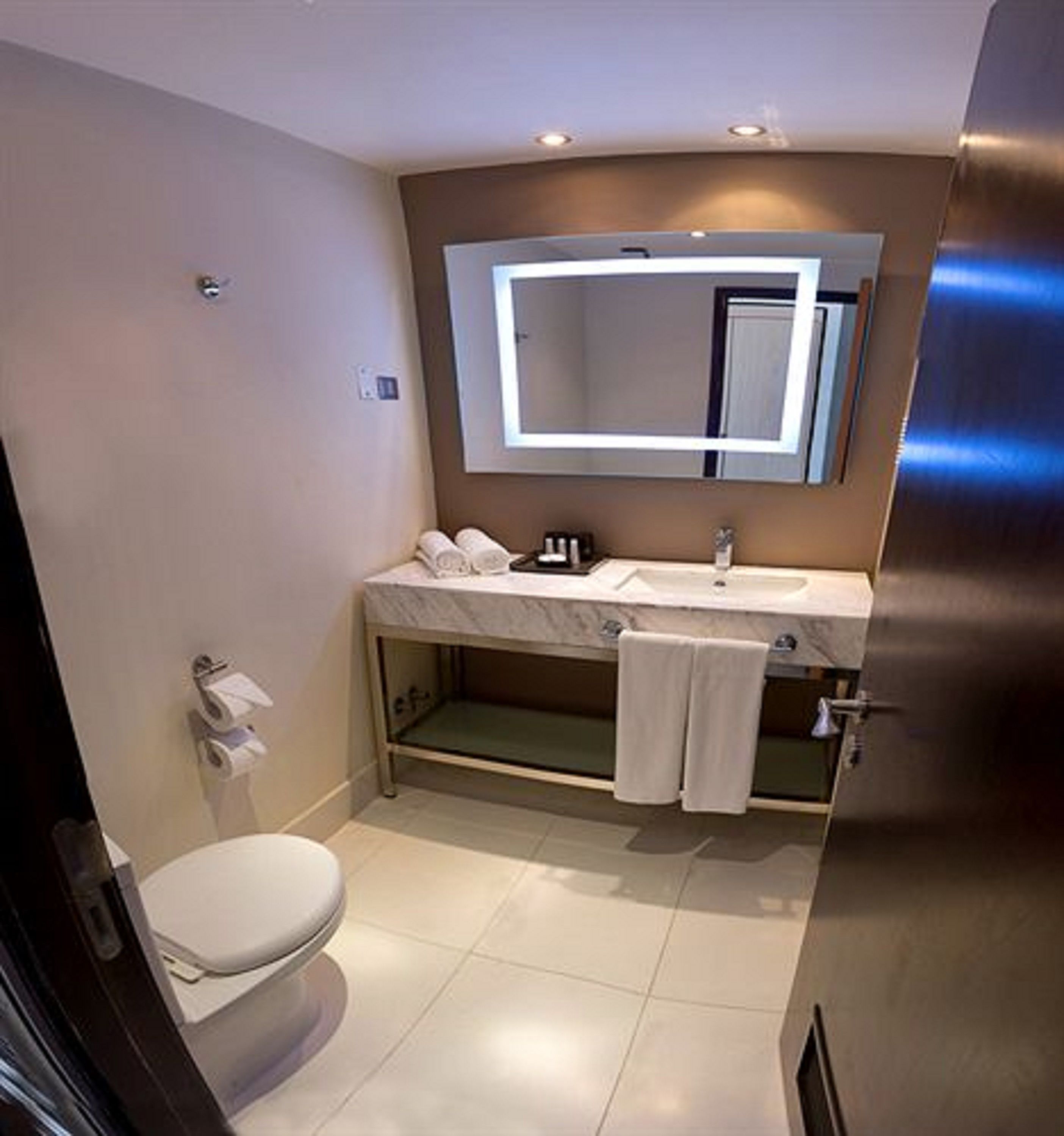 Un baño moderno con inodoro, lavamanos y espejo.