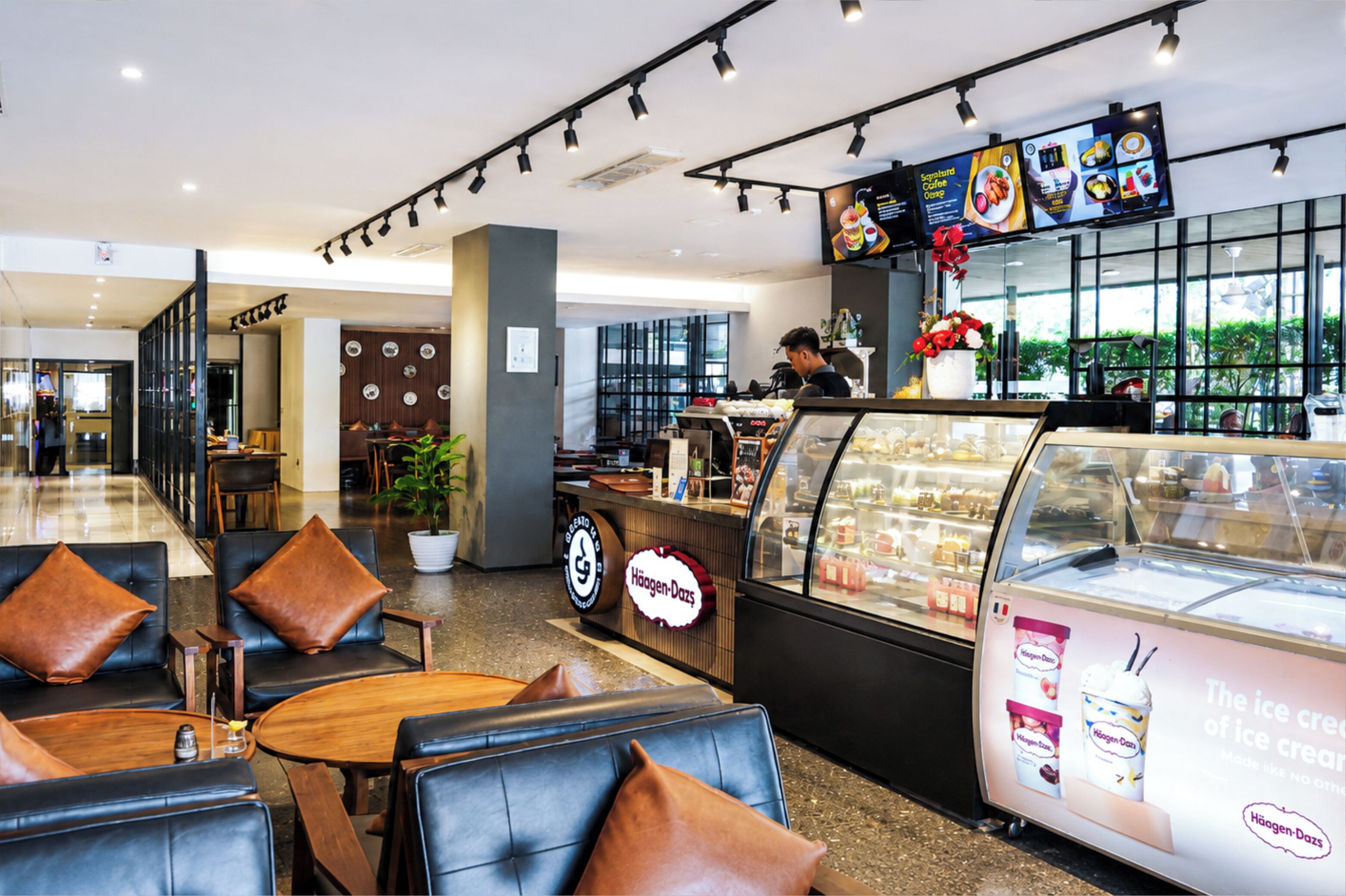 L'intérieur d'un café moderne, avec des tables, un comptoir et un présentoir pour afficher le menu.