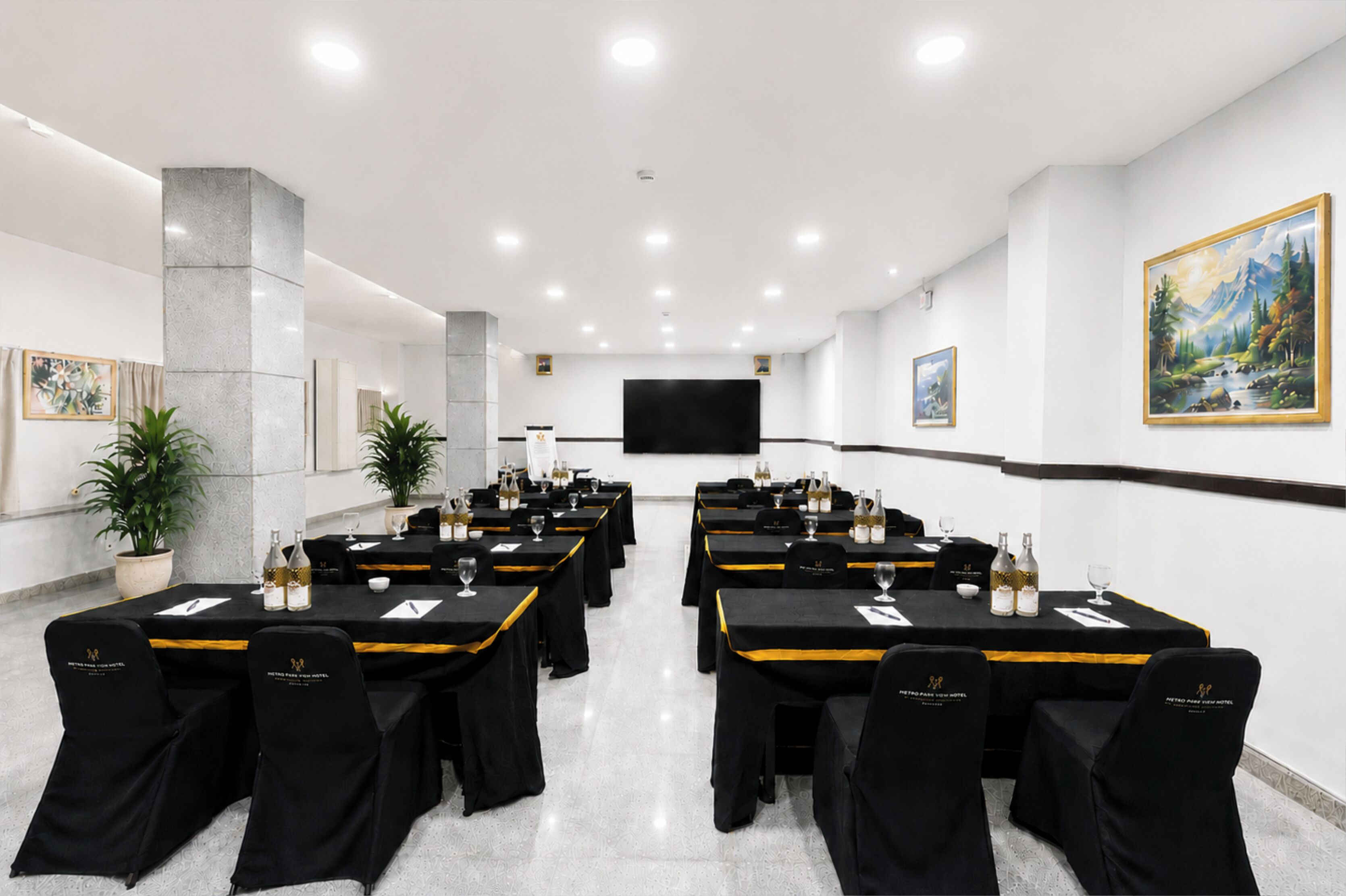 Un salón de conferencias con varias mesas, sillas y una pantalla grande.