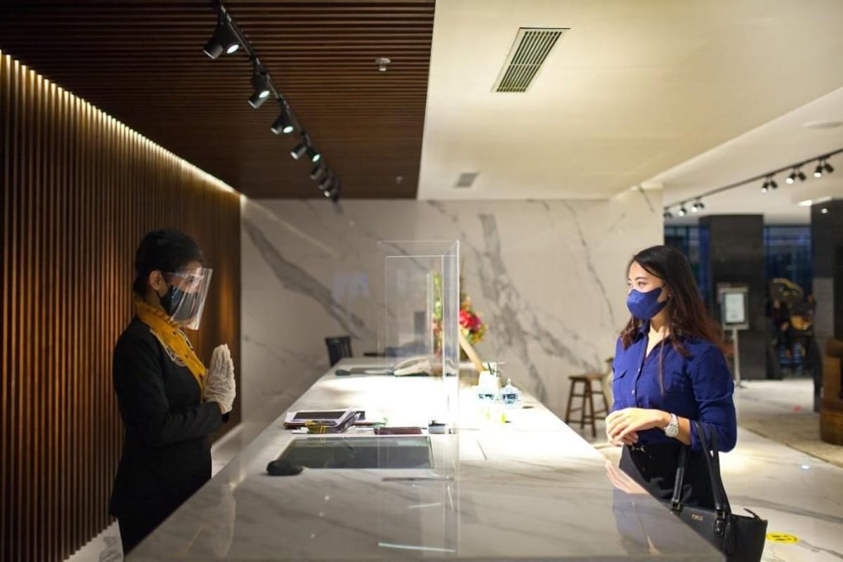A reception area with a marble counter, a wooden panel wall, and a modern ceiling design.