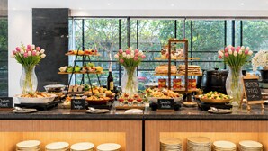 Een buffet met verschillende thematafels, waaronder aangegeven secties voor kip, aardappelpartjes, spaghetti en arrabiata.