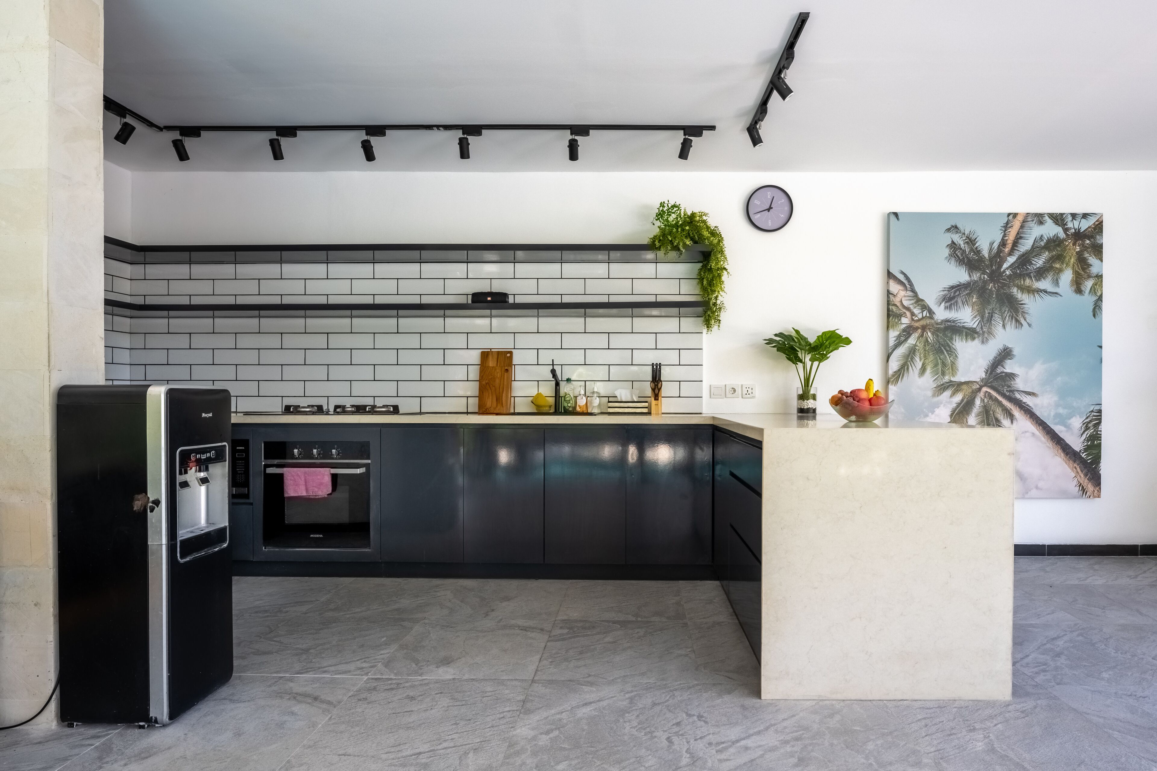 A modern kitchen with a black refrigerator, a built-in oven, and a tiled backsplash.