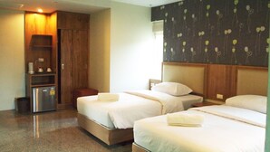 A hotel room with two beds, a wooden wardrobe, a small table, and a kitchenette. - Phuket Ecozy Hotel (Wichit)