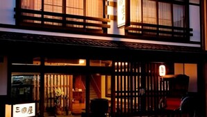 A traditional Japanese building with a wooden facade, large windows with curtains, and a sign indicating it is a restaurant. - Mikuniya (Toyooka)