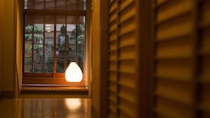 A corridor with a window featuring wooden blinds and a lit paper lantern. - Mikuniya (Toyooka)