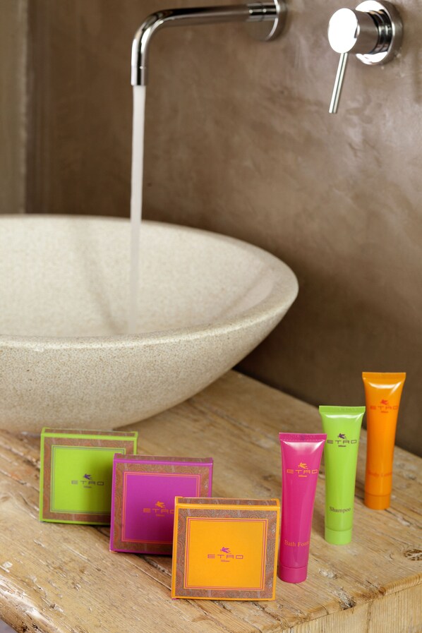 Un lavamanos con agua corriendo, rodeado de productos de baño coloridos.