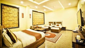 A hotel room with two single beds, a sofa, a TV, and a ceiling fan. - Royal View Hotel (Jaipur)