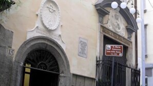 A building with a large arched entrance, a plaque, and a sign indicating a religious site. - Hotel Santa Brigida (Naples)